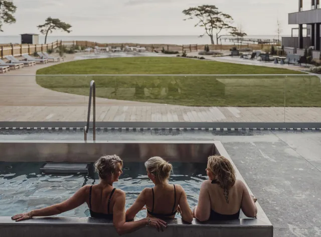 Drei Frauen sitzen in einem Pool mit Blick auf das Meer