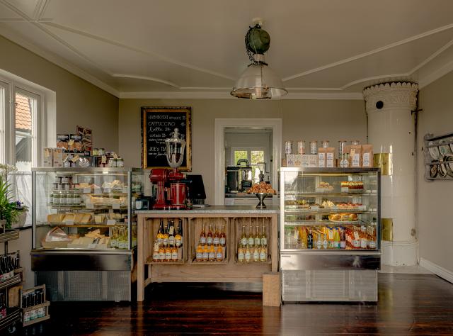 A well-stocked cafe counter with a traditional tiled ceramic stove located in the right-hand corner of the room.