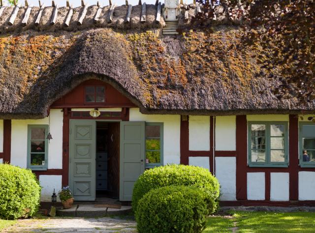 Entrance of an ancient farmhouse with traditional thatched roof, showing historical rural architecture