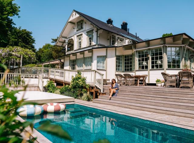 Large white villa with a swimming pool in the foreground on a sunny summer day