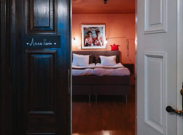 Open hotel room door revealing a spacious double bed inside the room